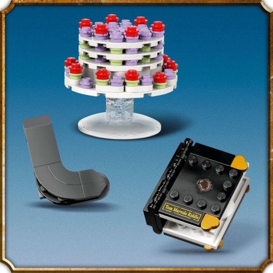 LEGO figurka Dobbyho stojí na podstavci se jmenovkou, drží Harryho ponožku v deníku Toma Riddla a vedle něj levituje pudinkový koláč tety Petunie.