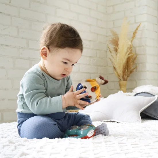 Barevné chrastítko ve tvaru kuličky s otvory pro snadné uchopení do rukou miminka