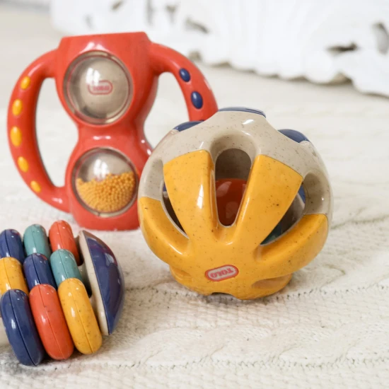 Barevné chrastítko ve tvaru kuličky s otvory pro snadné uchopení do rukou miminka