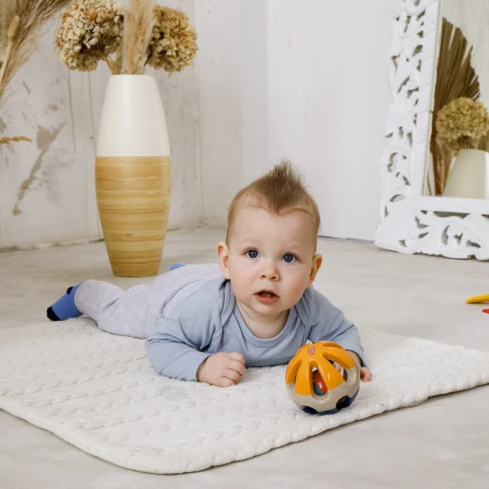 Barevné chrastítko ve tvaru kuličky s otvory pro snadné uchopení do rukou miminka