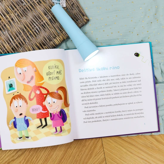 Skupina prvňáků s batohy na zádech stojí na lesní cestě, smějí se a ukazují si na mapě cestu k tábořišti.