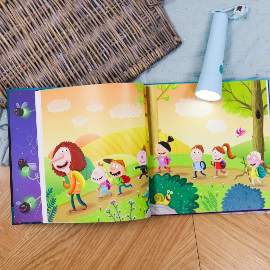 Skupina prvňáků s batohy na zádech stojí na lesní cestě, smějí se a ukazují si na mapě cestu k tábořišti.